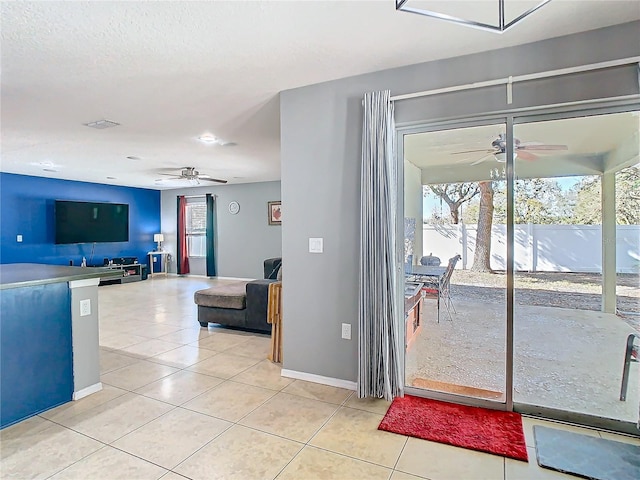 interior space featuring light tile patterned floors, ceiling fan, baseboards, and a textured ceiling