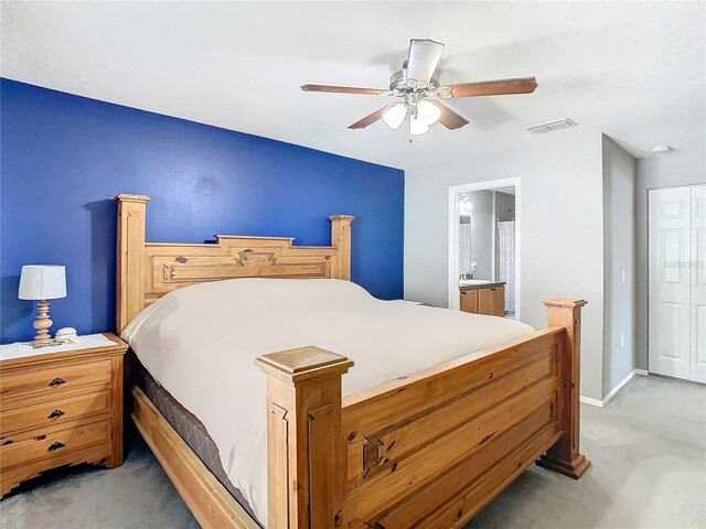 bedroom with light colored carpet, visible vents, ceiling fan, ensuite bath, and baseboards