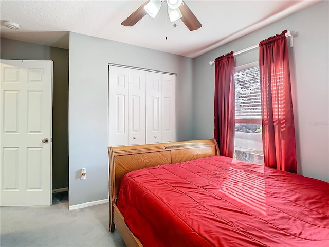 bedroom featuring light carpet, ceiling fan, baseboards, and a closet