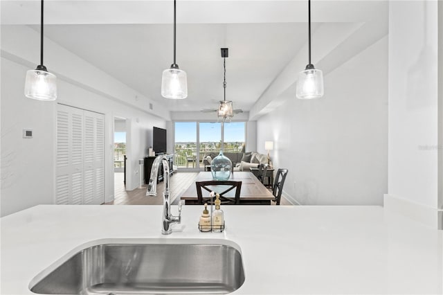 kitchen with light countertops, wood finished floors, a sink, and pendant lighting