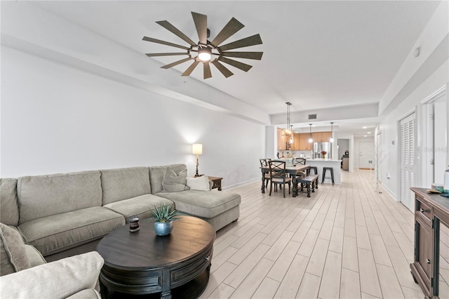 living area with light wood-style flooring, visible vents, baseboards, and a ceiling fan