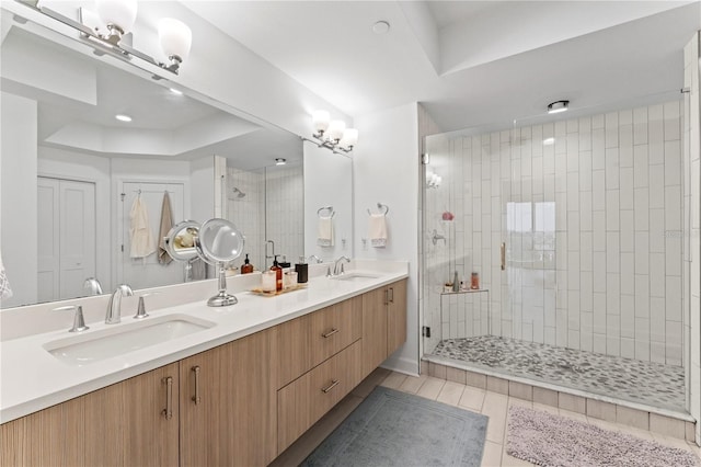 full bathroom featuring a raised ceiling, double vanity, a sink, and a shower stall