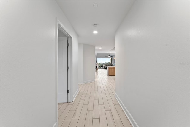 corridor with light wood finished floors and baseboards