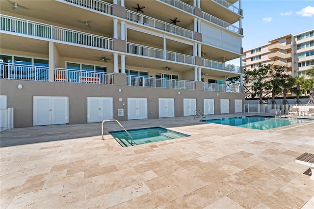 community pool featuring a patio area, fence, a ceiling fan, and a hot tub