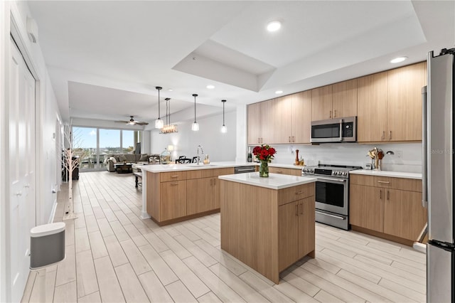 kitchen with light wood finished floors, open floor plan, a peninsula, stainless steel appliances, and light countertops