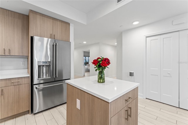 kitchen featuring high end fridge, a center island, light countertops, and recessed lighting