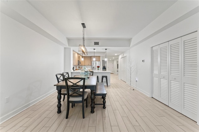 dining room featuring baseboards, visible vents, and light wood finished floors