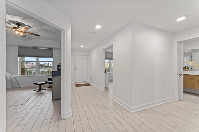 corridor with light wood-type flooring, baseboards, and recessed lighting