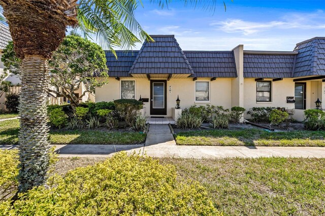 2101 Cordova Grn, Seminole, FL 33777 - view of property featuring stucco siding, a front lawn, and mansard roof