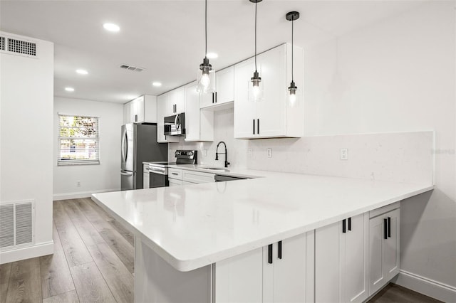 2101 Cordova Grn, Seminole, FL 33777 - kitchen with a peninsula, visible vents, white cabinets, hanging light fixtures, and appliances with stainless steel finishes