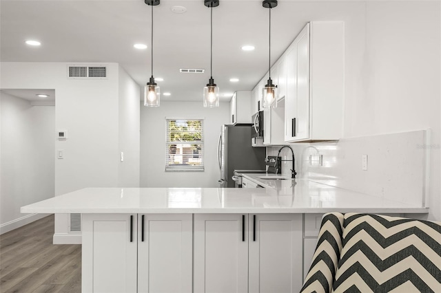2101 Cordova Grn, Seminole, FL 33777 - kitchen featuring a peninsula, visible vents, white cabinets, light countertops, and hanging light fixtures