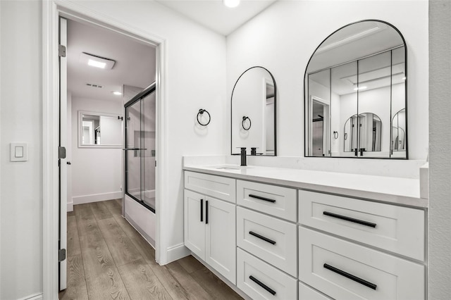 2101 Cordova Grn, Seminole, FL 33777 - bathroom featuring bath / shower combo with glass door, recessed lighting, vanity, wood finished floors, and baseboards