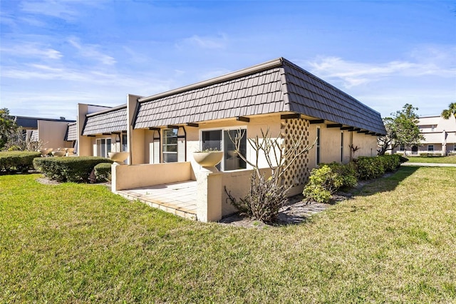 2101 Cordova Grn, Seminole, FL 33777 - view of side of property featuring stucco siding, a lawn, and mansard roof