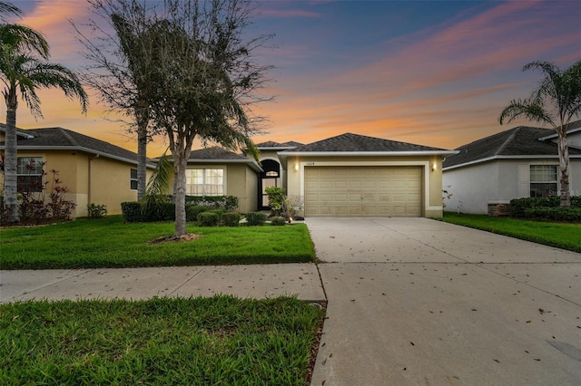 single story home with a garage, a yard, concrete driveway, and stucco siding