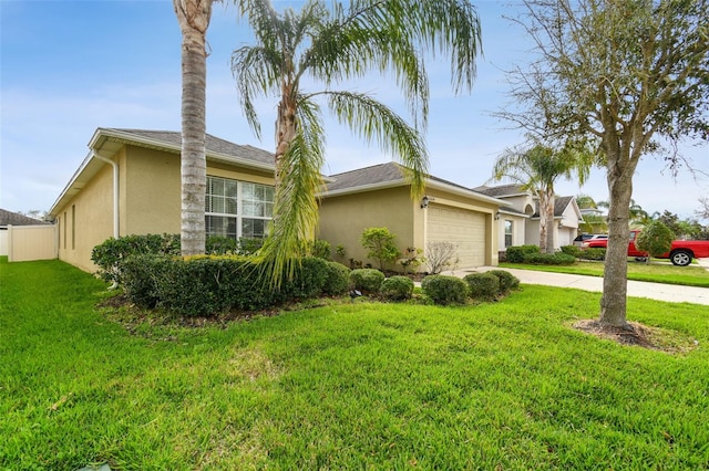 view of side of property featuring stucco siding, a lawn, an attached garage, fence, and driveway