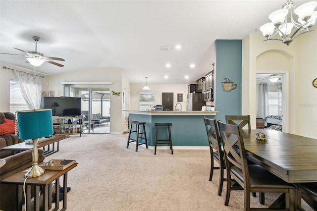 dining space with light carpet, vaulted ceiling, ceiling fan with notable chandelier, and recessed lighting