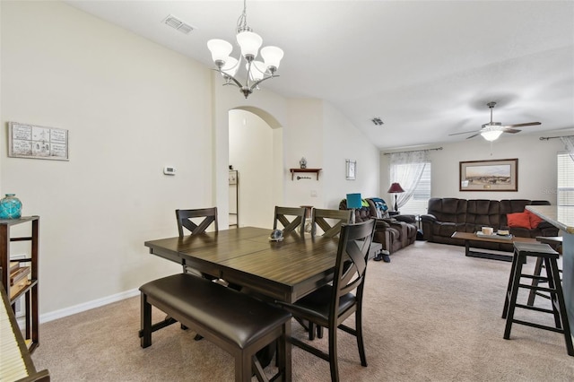 dining room featuring arched walkways, visible vents, light carpet, vaulted ceiling, and baseboards