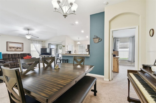 dining area with light colored carpet, vaulted ceiling, baseboards, and ceiling fan with notable chandelier