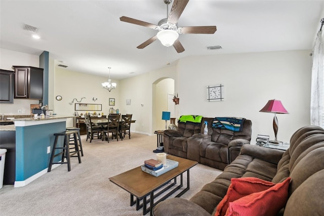 living room featuring arched walkways, ceiling fan with notable chandelier, light carpet, visible vents, and vaulted ceiling