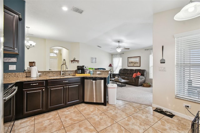 kitchen featuring stainless steel appliances, a sink, open floor plan, dark brown cabinets, and decorative light fixtures