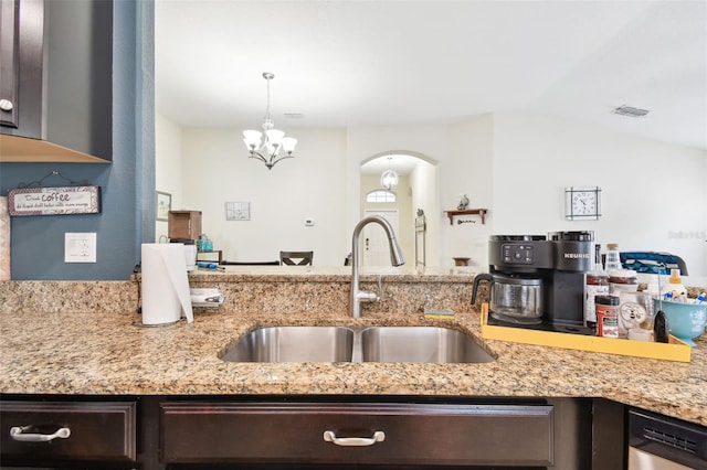 kitchen with dark brown cabinetry, dishwasher, light stone counters, pendant lighting, and a sink