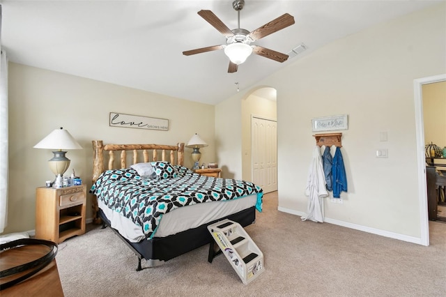 bedroom with arched walkways, lofted ceiling, a closet, visible vents, and baseboards