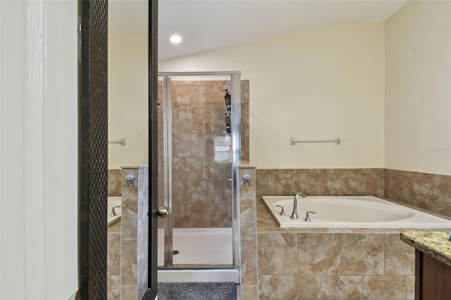 bathroom featuring lofted ceiling, a stall shower, a garden tub, and vanity