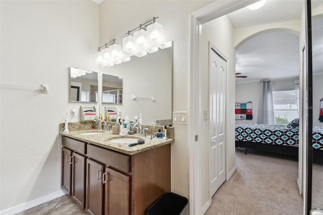 ensuite bathroom with ensuite bathroom, double vanity, a sink, and baseboards