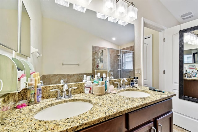 bathroom with lofted ceiling, visible vents, a sink, and a shower stall