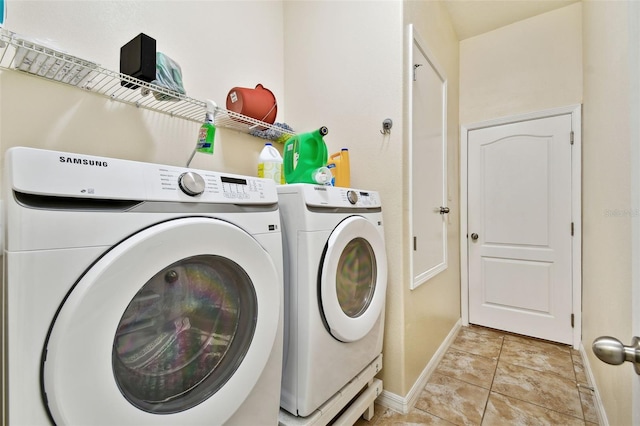 washroom with light tile patterned floors, laundry area, baseboards, and washer and dryer