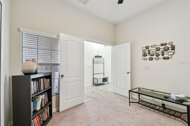 interior space with baseboards, a ceiling fan, and light colored carpet