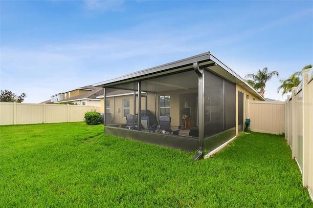 rear view of property featuring a sunroom, a fenced backyard, and a yard