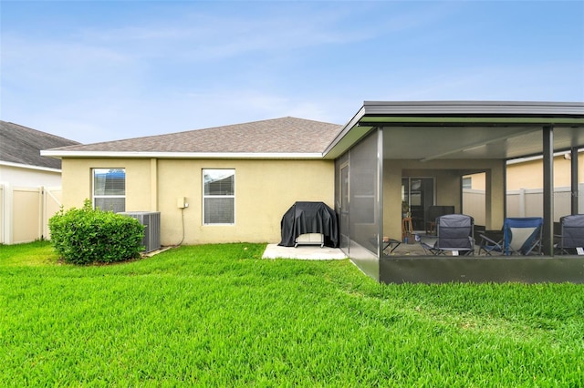 back of house featuring a yard, stucco siding, central AC unit, a sunroom, and fence