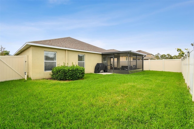 back of house with a sunroom, a fenced backyard, stucco siding, and a yard