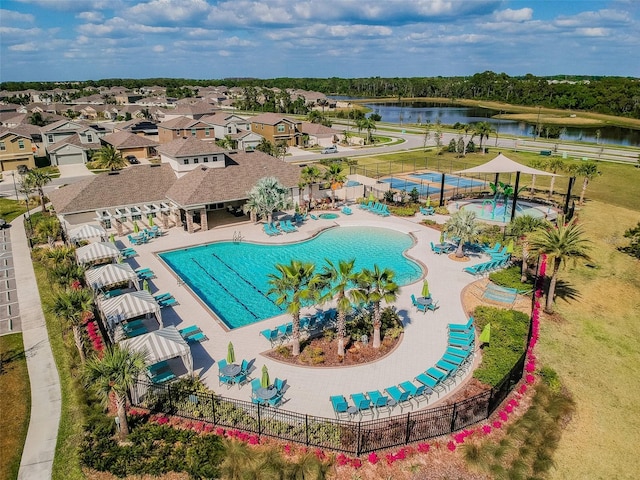 community pool with a patio, a water view, fence, and a residential view