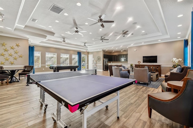 rec room with wood tiled floor, a raised ceiling, visible vents, and crown molding