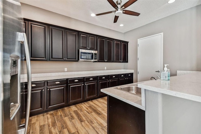 kitchen with light wood finished floors, light countertops, appliances with stainless steel finishes, a sink, and ceiling fan