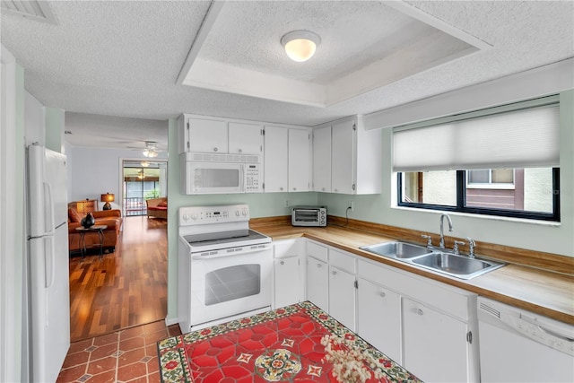 kitchen featuring white appliances, plenty of natural light, a raised ceiling, and a sink