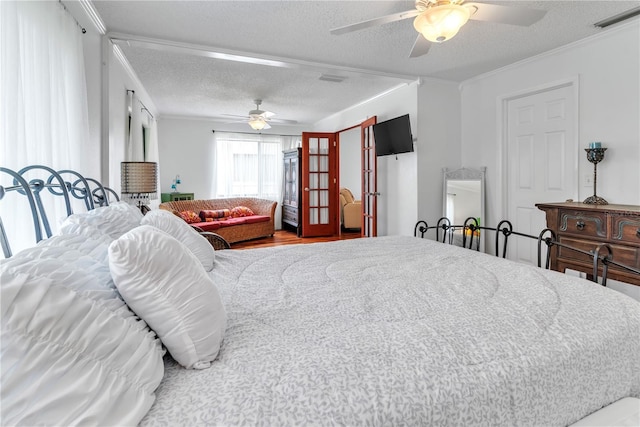 bedroom with a ceiling fan, visible vents, ornamental molding, and a textured ceiling