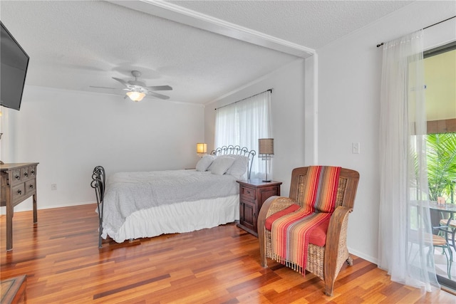 bedroom featuring a textured ceiling, ceiling fan, wood finished floors, and baseboards