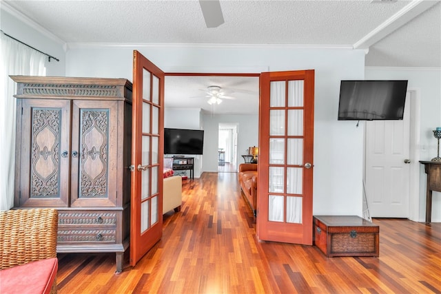 interior space with french doors, crown molding, a textured ceiling, and wood finished floors