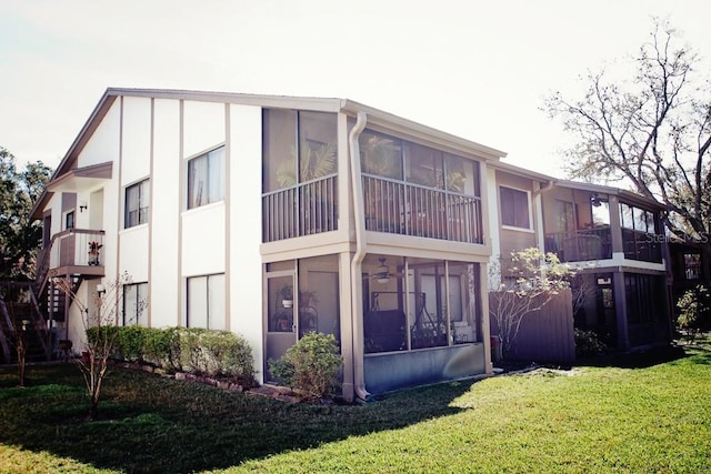 rear view of house featuring a sunroom and a yard