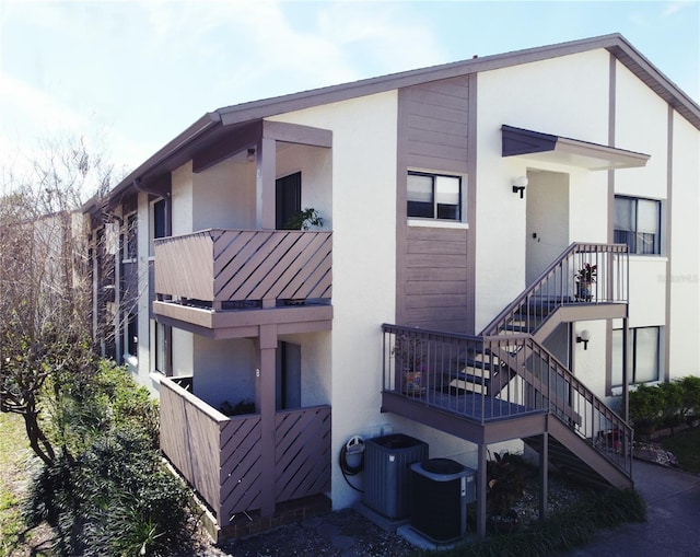 exterior space featuring stairway, stucco siding, and central air condition unit