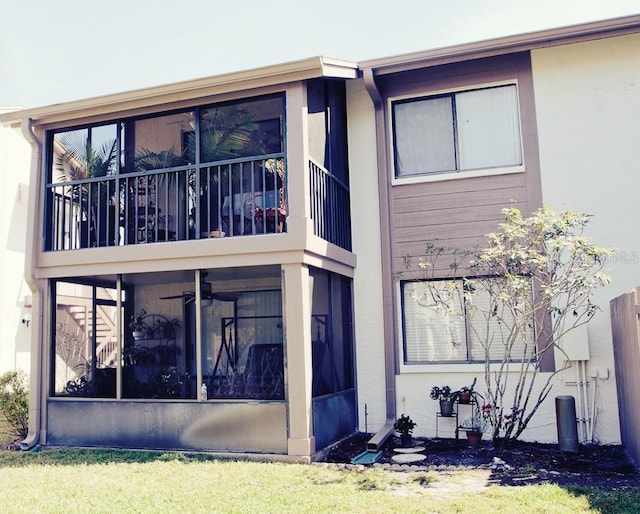 exterior space with a balcony, a sunroom, and stucco siding