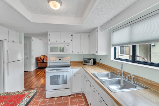 kitchen with white appliances, light countertops, a sink, and white cabinets