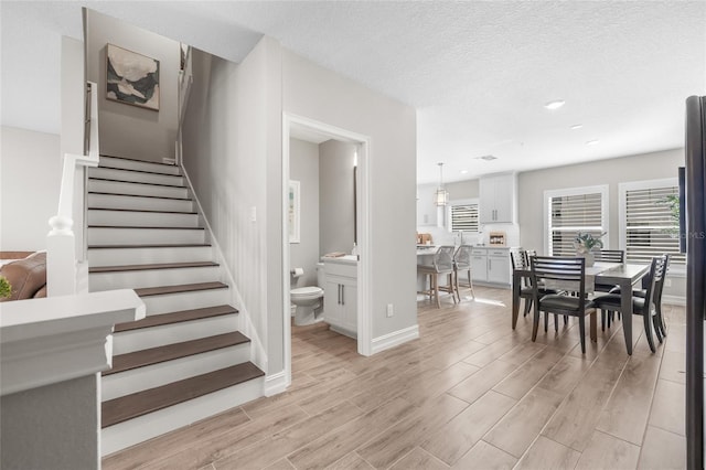 interior space with a textured ceiling, recessed lighting, baseboards, stairs, and light wood-type flooring