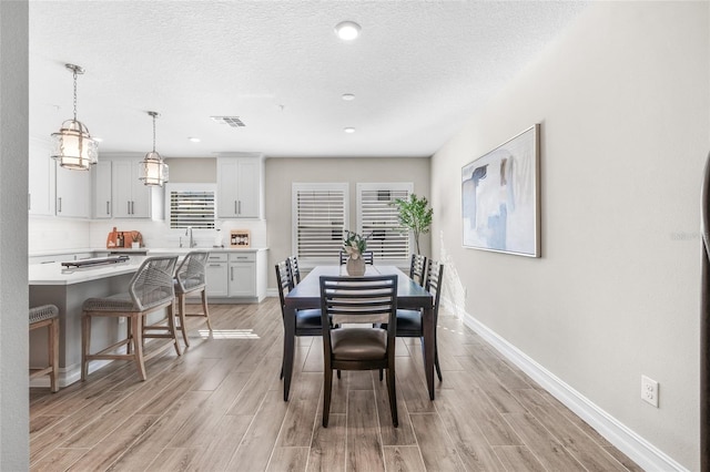 dining room with light wood finished floors, baseboards, and visible vents