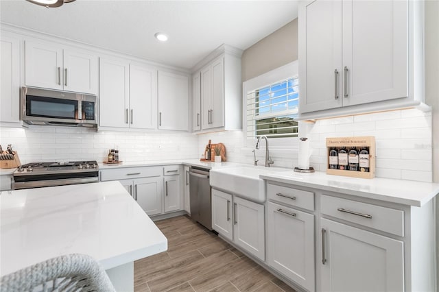 kitchen featuring decorative backsplash, stainless steel appliances, light wood-style floors, a sink, and recessed lighting