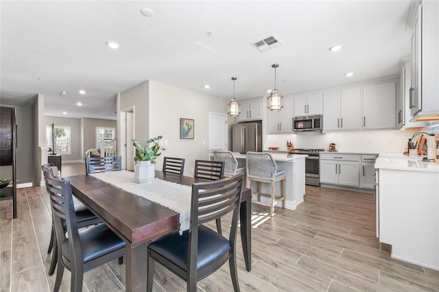 dining room with recessed lighting, visible vents, light wood-style flooring, and baseboards