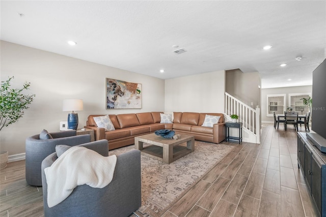 living room featuring wood tiled floor, stairs, baseboards, and recessed lighting